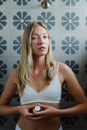 person standing in front of tiles holding naked tallow lip balm