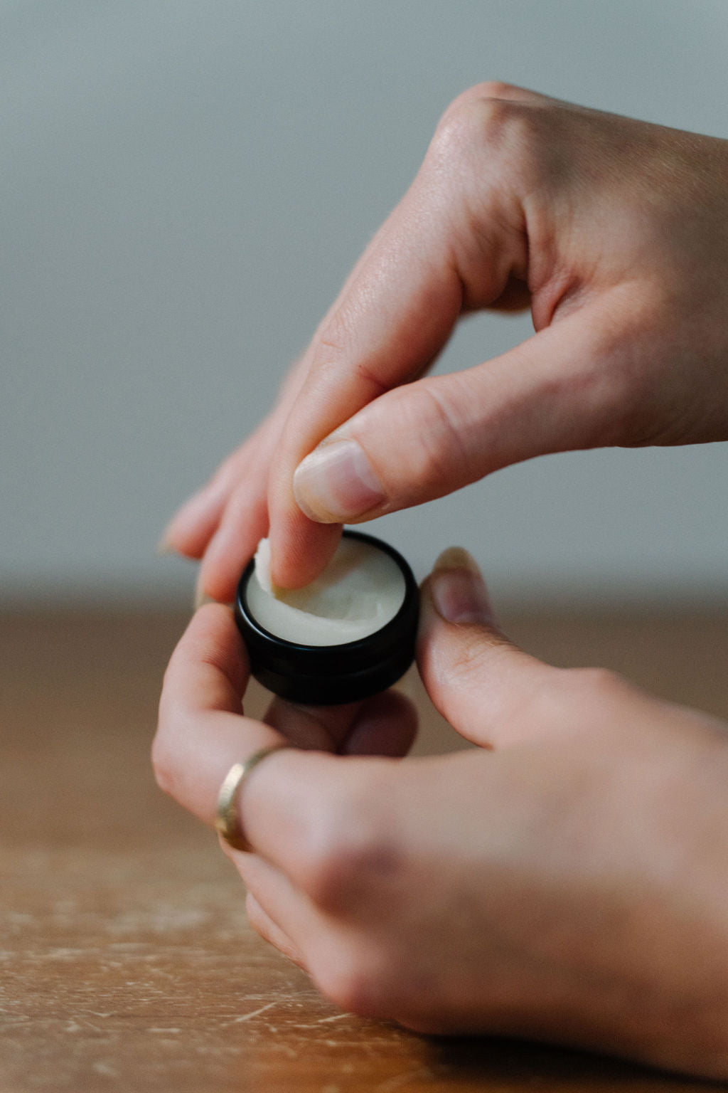 person getting tallow lip balm out of circle container