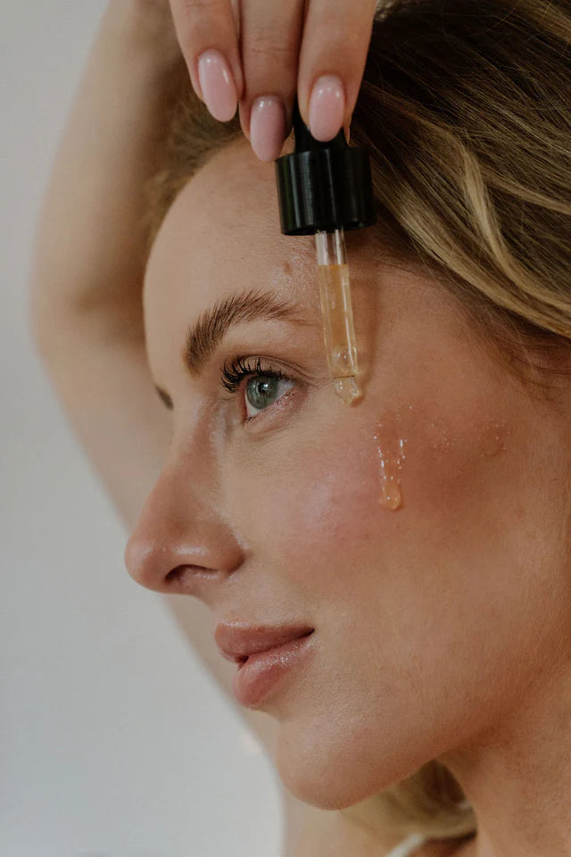 Woman applying a dropper of skincare product to her face - deeply moisturising beef tallow serum for dry and sensitive skin, made in Australia.