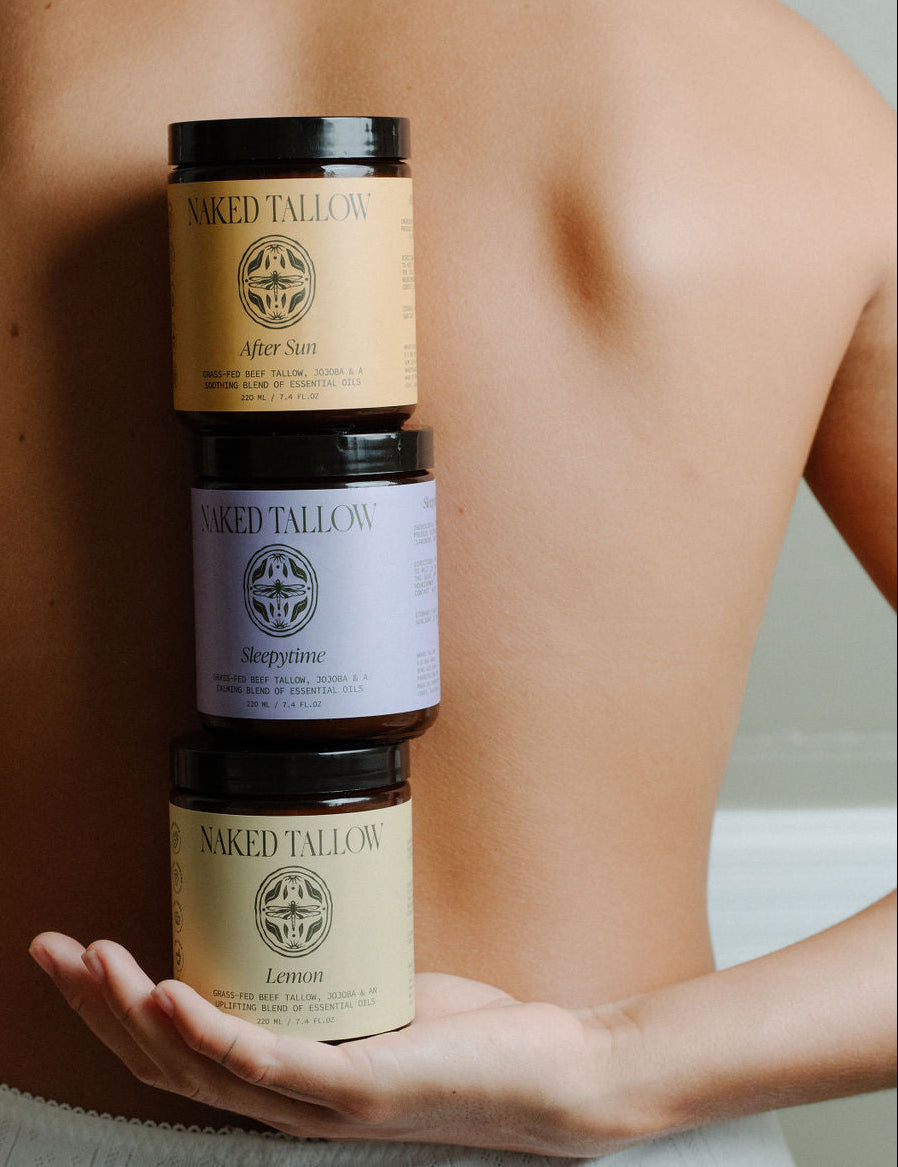 Three jars of scented tallow cream held in a person's hand, with labels indicating different scents.